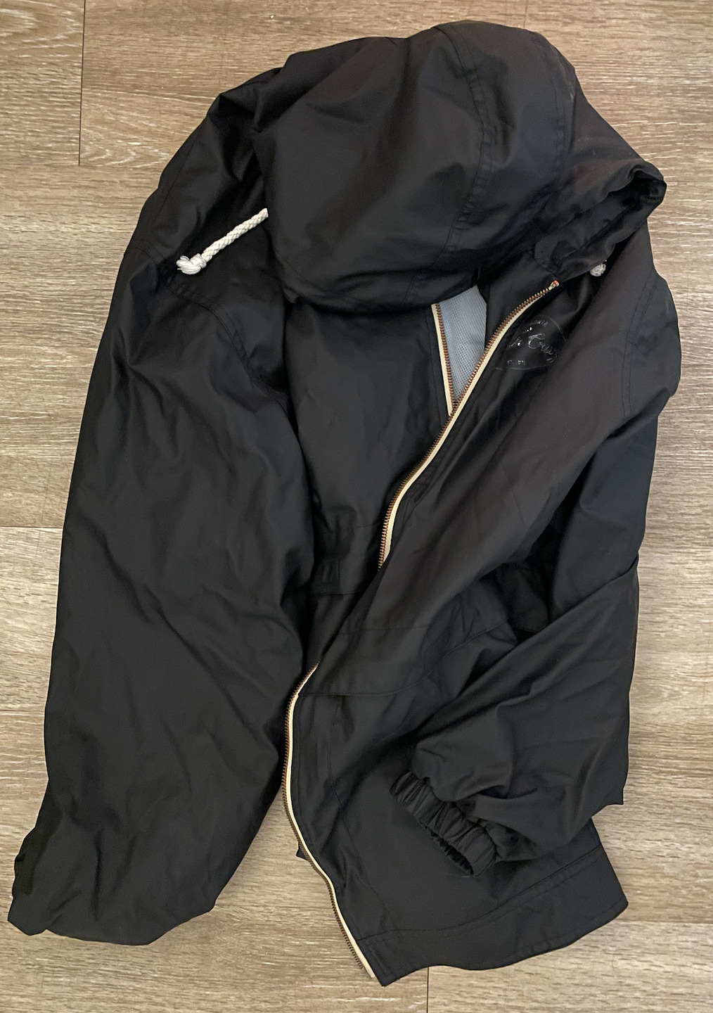 A black windbreaker with a brass zipper and white drawstrings